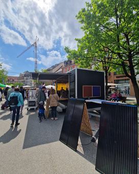 Das Energiemobil steht in der Altstadt von Ravensburg, Menschen schlendern vorbei, einige bleiben am Mobil stehen.